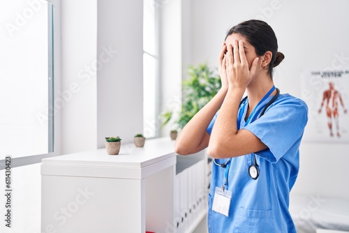 Young beautiful hispanic woman doctor stressed standing at clinic