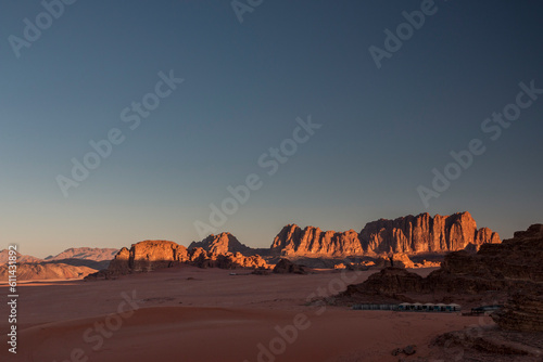 sunrise over the desert camp with Jebel Qatar sandstone cliffs in the background, Wadi Rum, Jordan