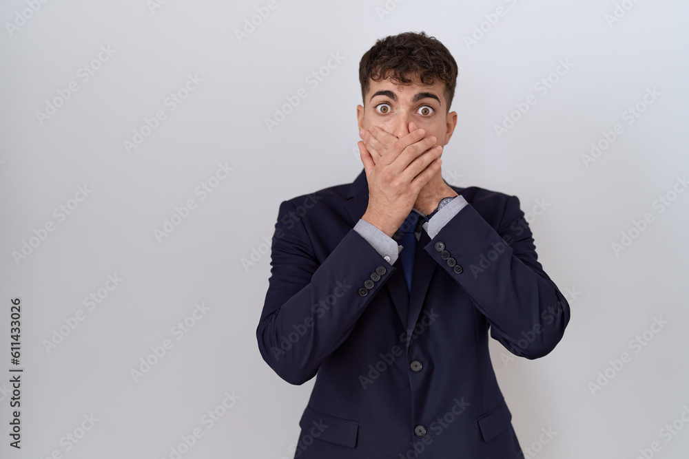 Young hispanic business man wearing suit and tie shocked covering mouth with hands for mistake. secret concept. Young hispanic business man wearing suit and tie shocked covering mouth with hands for mistake. secret concept.