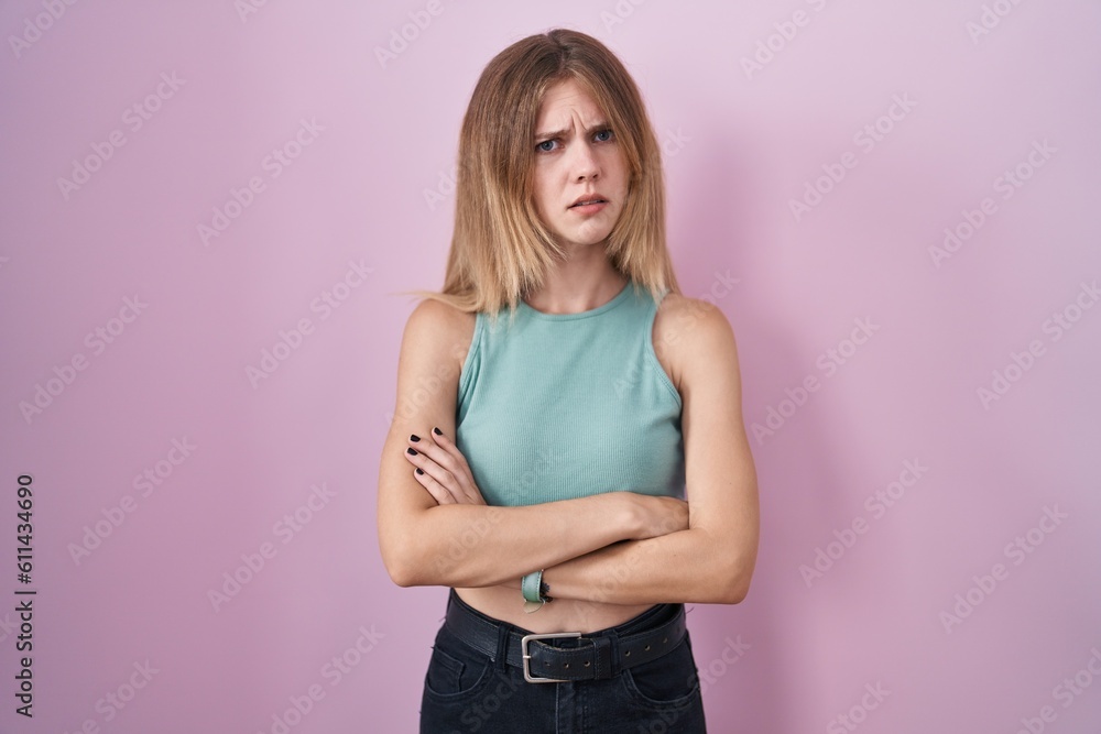 Blonde caucasian woman standing over pink background skeptic and nervous, disapproving expression on face with crossed arms. negative person. Blonde caucasian woman standing over pink background skeptic and nervous, disapproving expression on face with crossed arms. negative person.