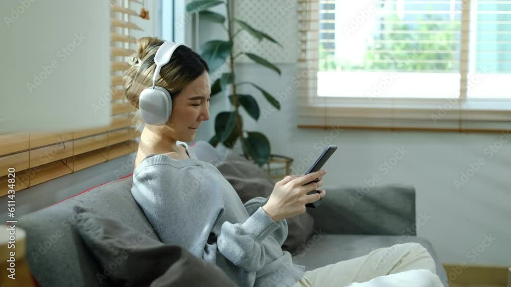 Side view of joyful young woman wearing headphone playing video game on digital tablet at home Side view of joyful young woman wearing headphone playing video game on digital tablet at home