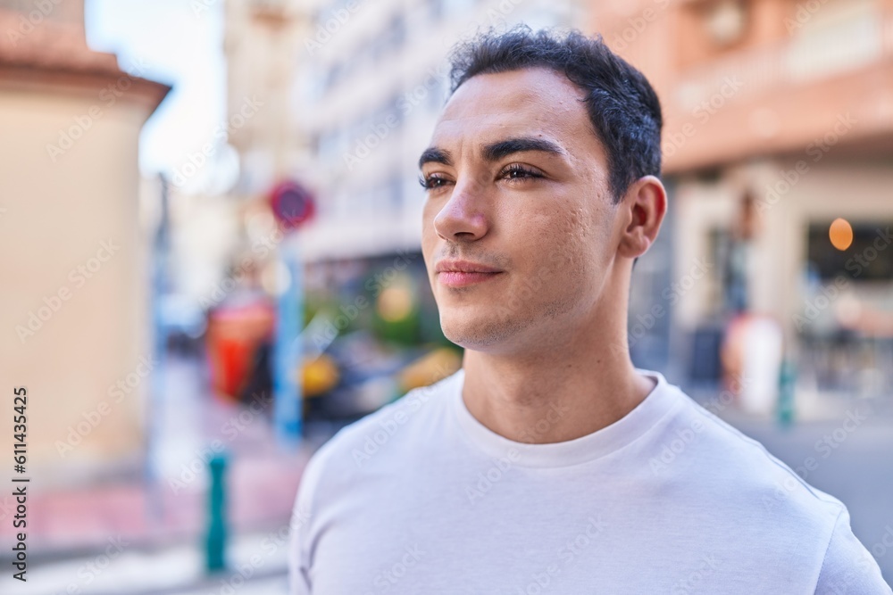 Young hispanic man looking to the side with serious expression at street Young hispanic man looking to the side with serious expression at street