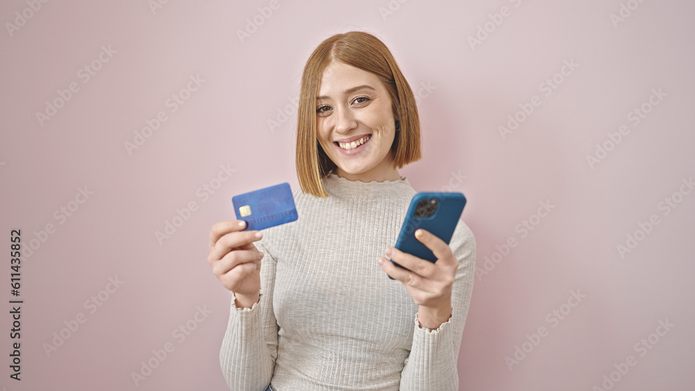 Young blonde woman shopping with smartphone and credit card over isolated pink background