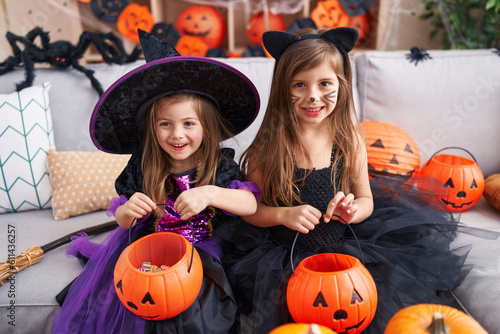Adorable girls having halloween party holding pumpkin basket at home