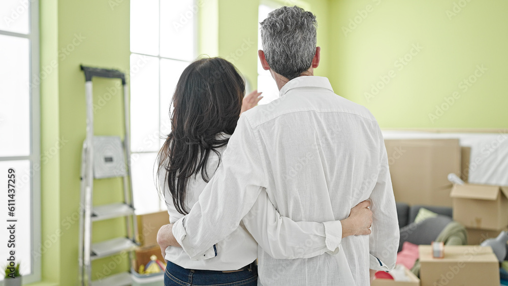 Senior man and woman couple hugging each other looking around at new home Senior man and woman couple hugging each other looking around at new home