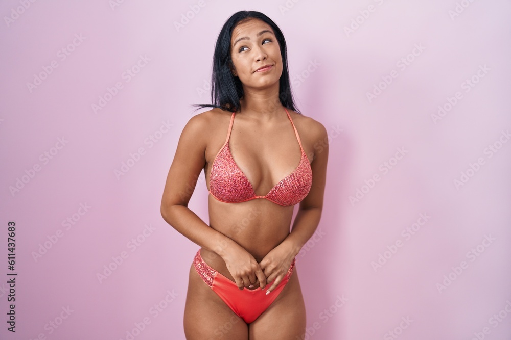 Hispanic woman wearing bikini smiling looking to the side and staring away thinking. Hispanic woman wearing bikini smiling looking to the side and staring away thinking.
