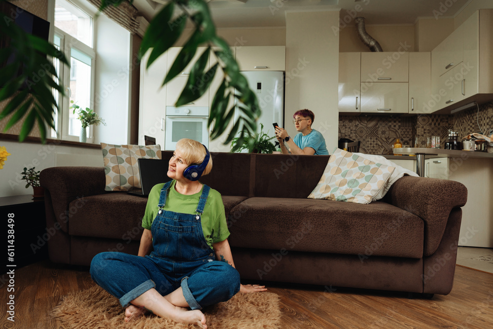 Beautiful elderly woman in headphones sitting on the living room floor Beautiful elderly woman in headphones sitting on the living room floor