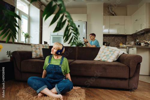 Beautiful elderly woman in headphones sitting on the living room floor