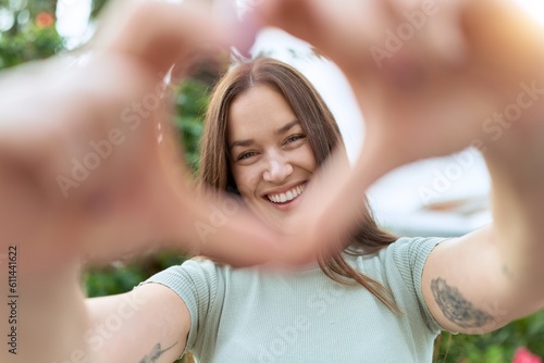 Young beautiful woman smiling confident doing heart gesture with hands at park