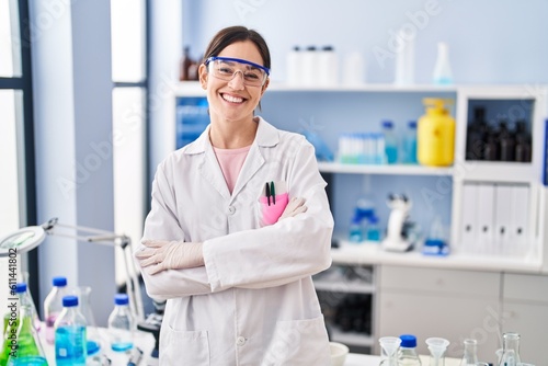 Fototapeta Naklejka Na Ścianę i Meble -  Young brunette woman working at scientist laboratory happy face smiling with crossed arms looking at the camera. positive person.