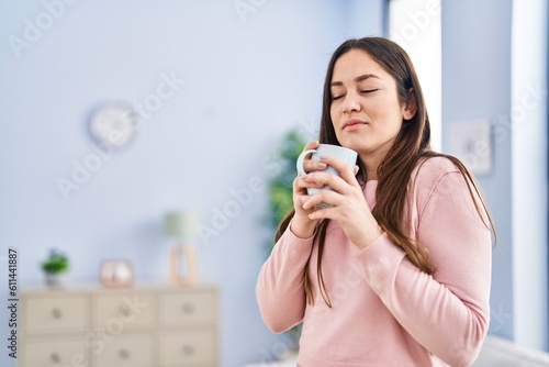 Fototapeta Naklejka Na Ścianę i Meble -  Young woman smelling cup of coffee at home