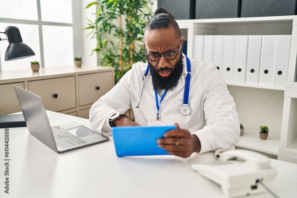 African american man working on online appointment scared and amazed with open mouth for surprise, disbelief face African american man working on online appointment scared and amazed with open mouth for surprise, disbelief face