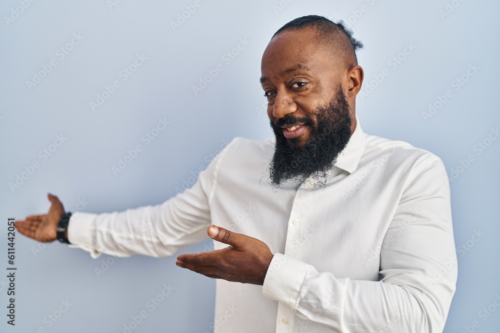 African american man standing over blue background inviting to enter smiling natural with open hand African american man standing over blue background inviting to enter smiling natural with open hand