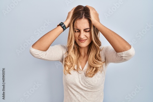 Young blonde woman standing over isolated background suffering from headache desperate and stressed because pain and migraine. hands on head. © Krakenimages.com