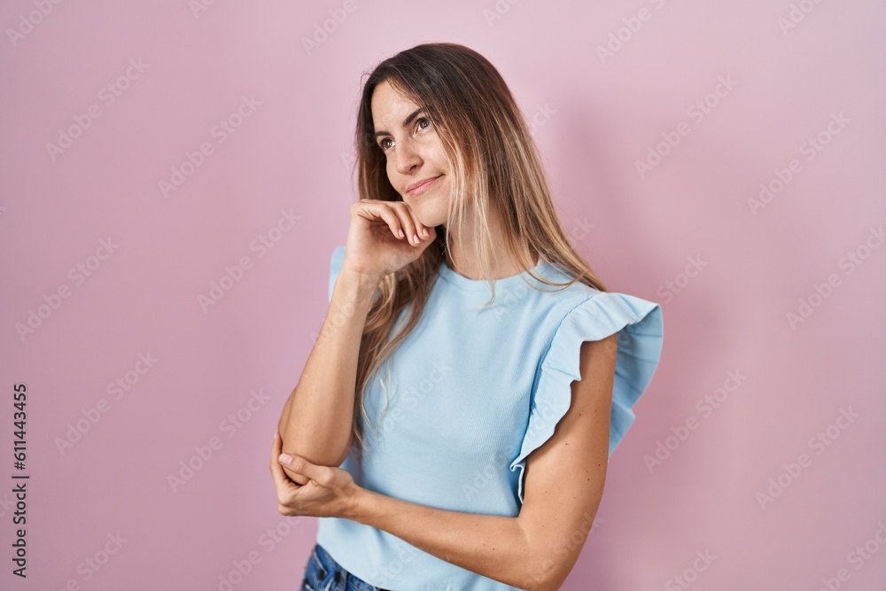 Young hispanic woman standing over pink background with hand on chin thinking about question, pensive expression. smiling with thoughtful face. doubt concept. Young hispanic woman standing over pink background with hand on chin thinking about question, pensive expression. smiling with thoughtful face. doubt concept.
