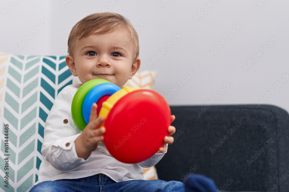 Naklejka premium Adorable caucasian boy playing with hoops game sitting on sofa at home