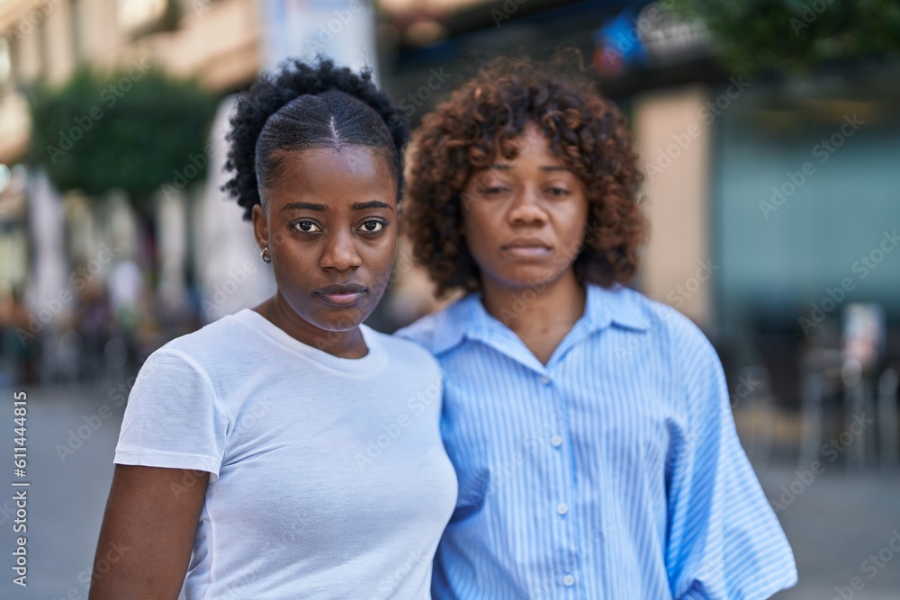 African american women mother and daughter standing together with serious expression at street