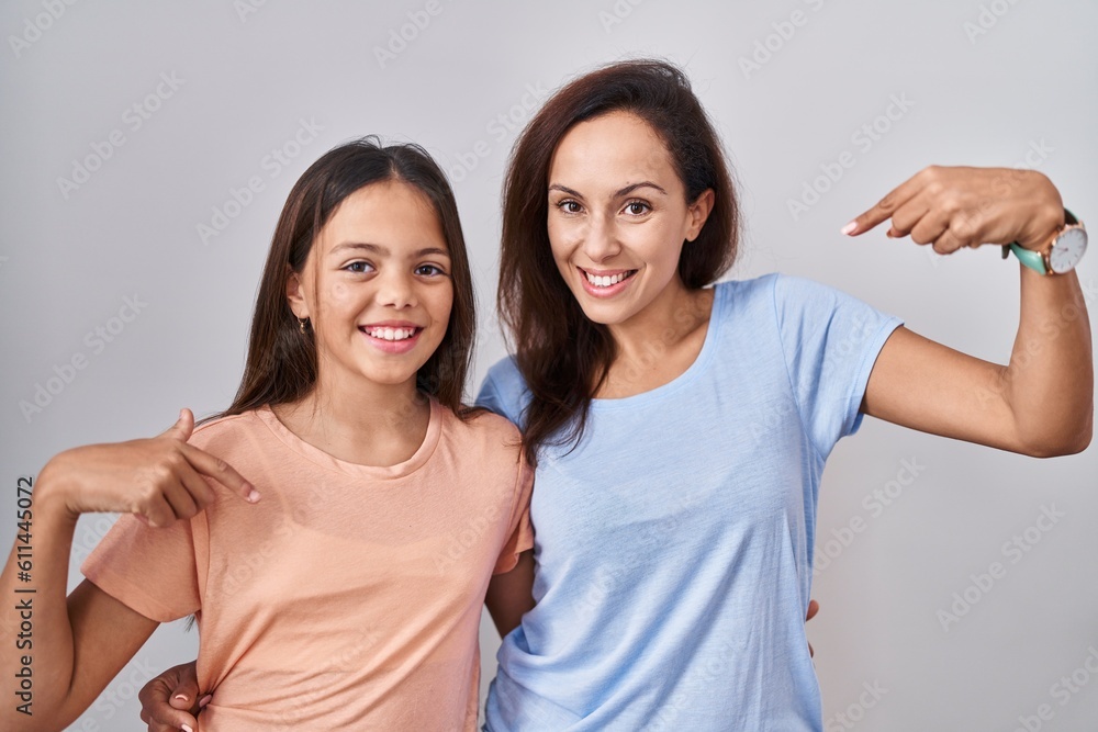 Young mother and daughter standing over white background looking confident with smile on face, pointing oneself with fingers proud and happy. Young mother and daughter standing over white background looking confident with smile on face, pointing oneself with fingers proud and happy.