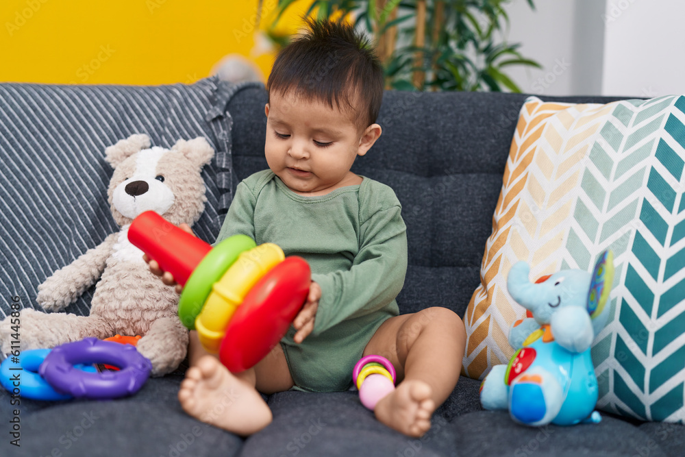 Adorable hispanic boy playing with hoops game sitting on sofa at home Adorable hispanic boy playing with hoops game sitting on sofa at home
