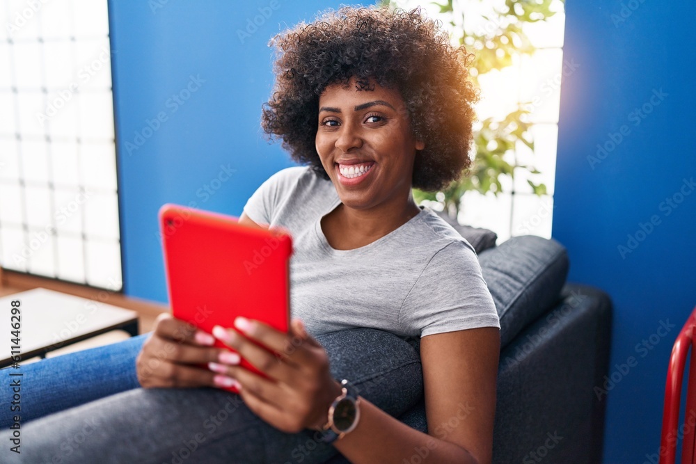 African american woman using touchpad sitting on sofa at home African american woman using touchpad sitting on sofa at home