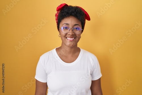 Young african american woman standing over yellow background with a happy and cool smile on face. lucky person.