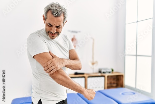 Photography Middle age grey-haired man patient suffering for arm pain standing at rehab clin