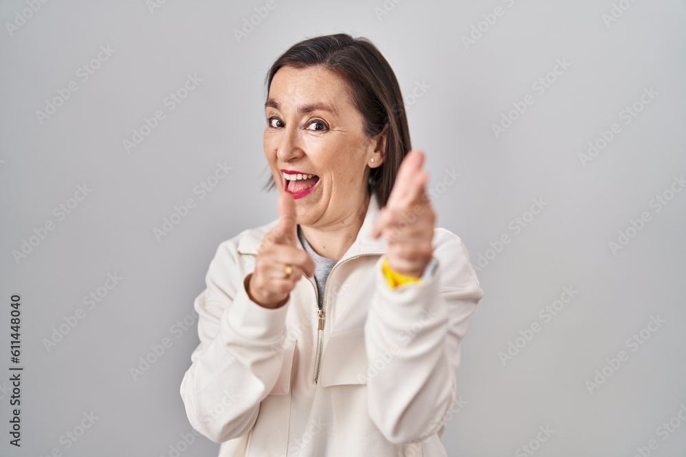 Middle age hispanic woman standing over isolated background pointing fingers to camera with happy and funny face. good energy and vibes. Middle age hispanic woman standing over isolated background pointing fingers to camera with happy and funny face. good energy and vibes.