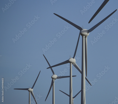 Isolated group of wind turbines in foreground and clean blue sky in the background