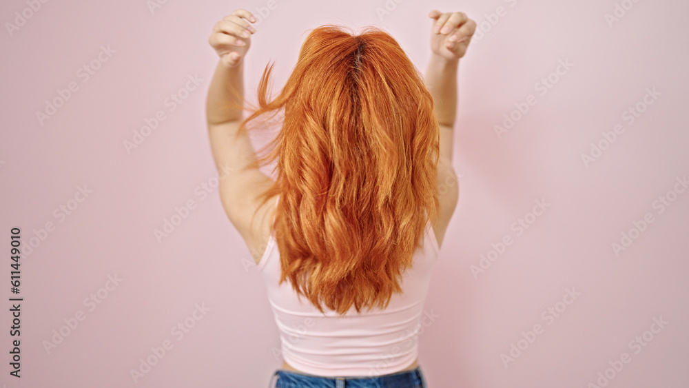 Young redhead woman touching her hair backwards over isolated pink background Young redhead woman touching her hair backwards over isolated pink background