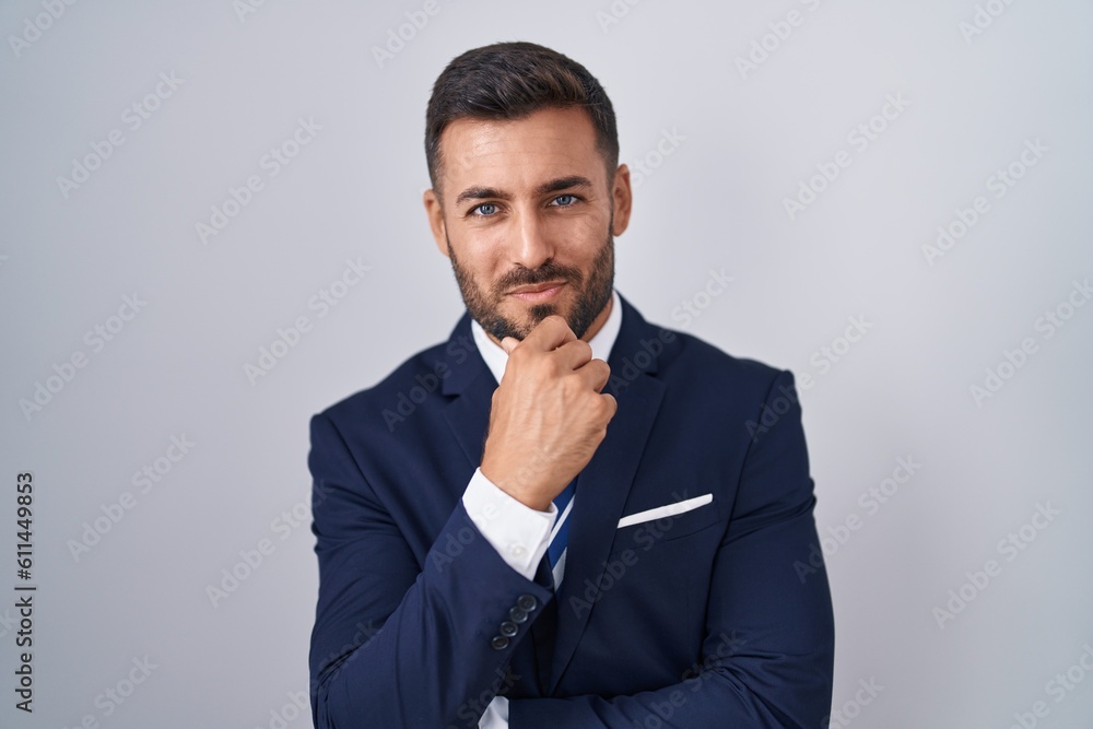 Handsome hispanic man wearing suit and tie looking confident at the camera smiling with crossed arms and hand raised on chin. thinking positive. Handsome hispanic man wearing suit and tie looking confident at the camera smiling with crossed arms and hand raised on chin. thinking positive.