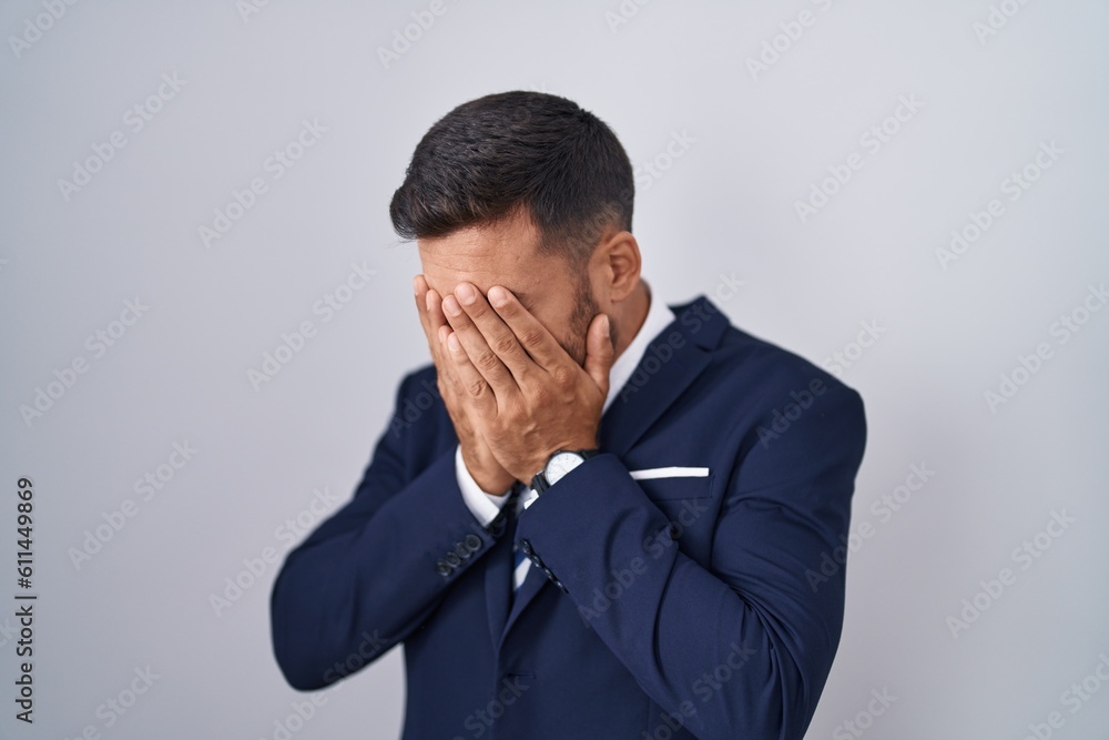 Handsome hispanic man wearing suit and tie with sad expression covering face with hands while crying. depression concept. Handsome hispanic man wearing suit and tie with sad expression covering face with hands while crying. depression concept.