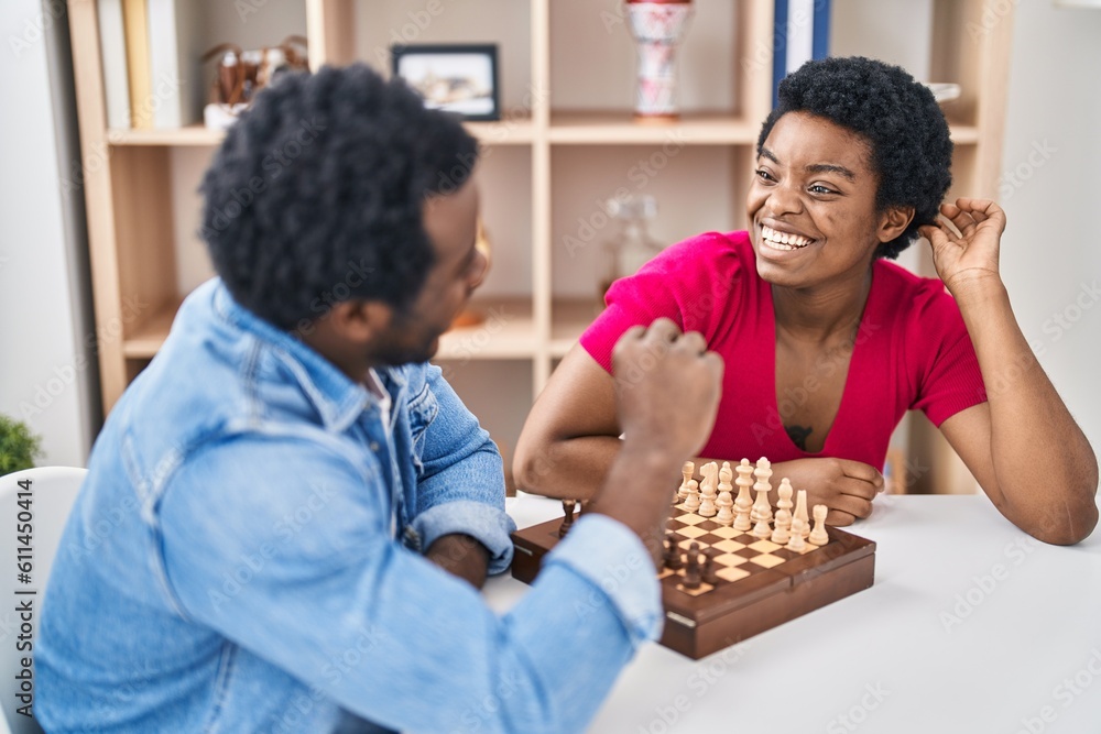 African american man and woman couple playing chess sitting on table at home