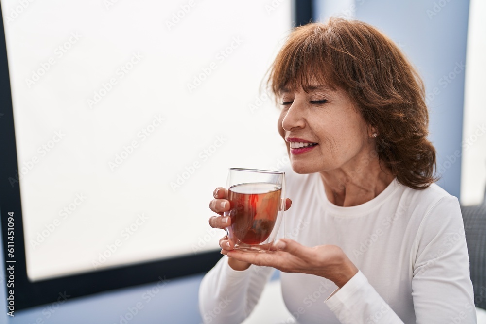 Middle age woman drinking tea sitting on sofa at home Middle age woman drinking tea sitting on sofa at home
