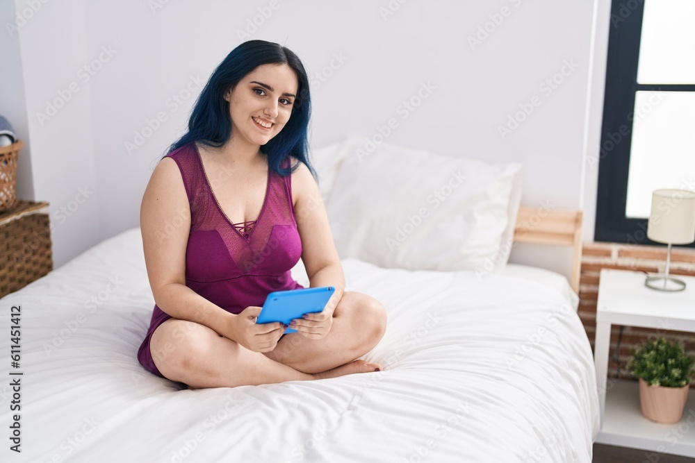 Young caucasian woman using touchpad sitting on bed at bedroom Young caucasian woman using touchpad sitting on bed at bedroom