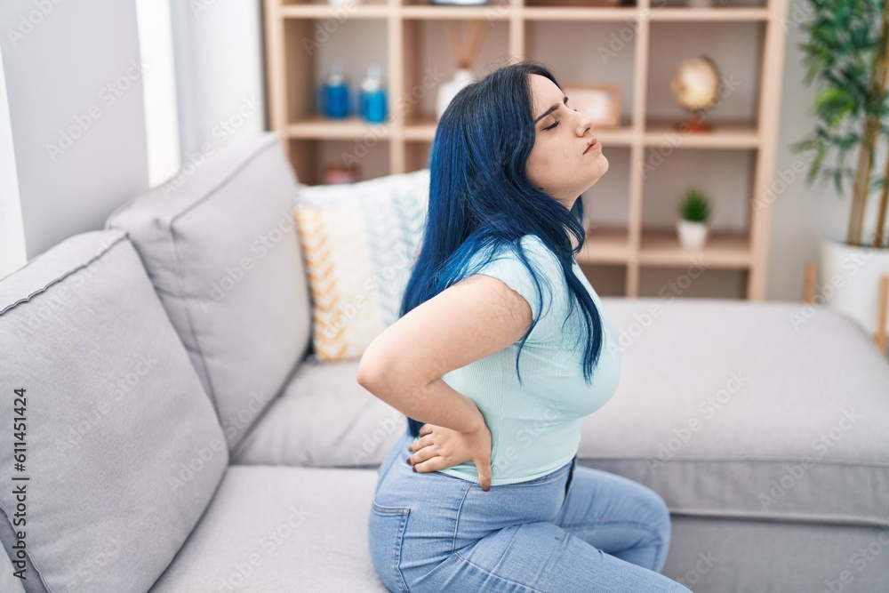 Young caucasian woman suffering for backache sitting on sofa at home Young caucasian woman suffering for backache sitting on sofa at home