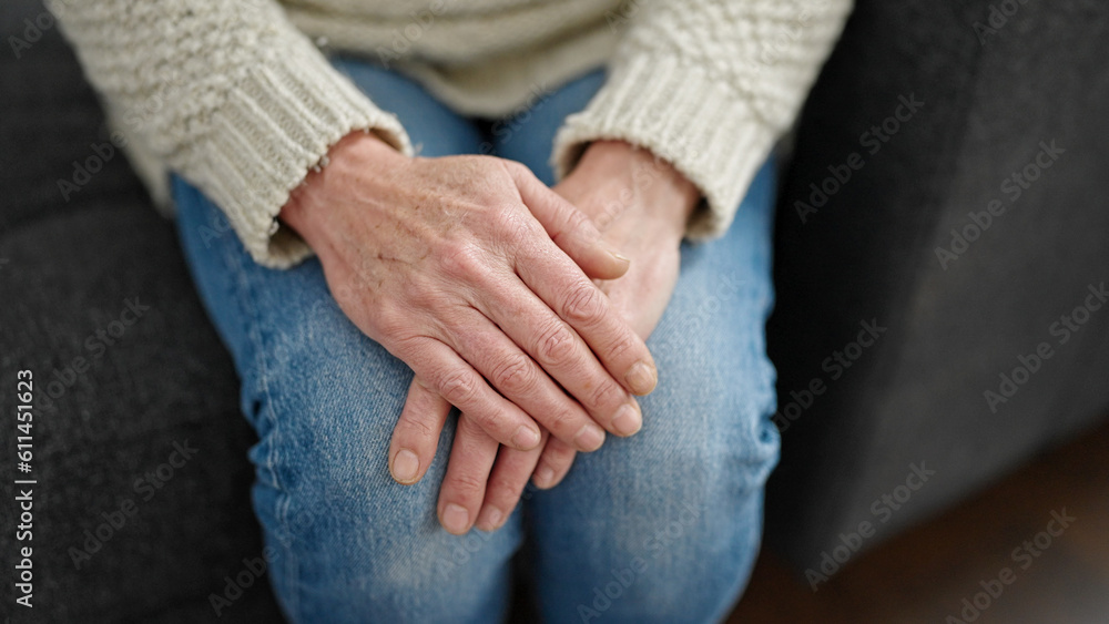 Mature hispanic woman with hands over knees at home