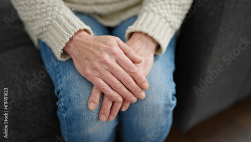 Mature hispanic woman with hands over knees at home