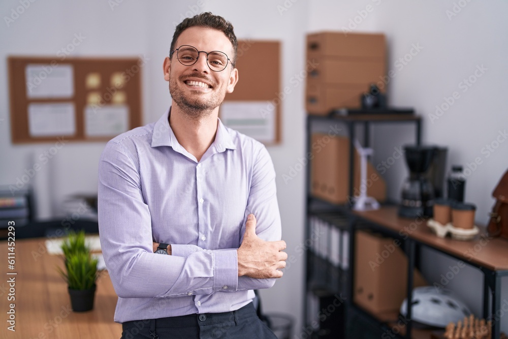 Young hispanic man at the office happy face smiling with crossed arms looking at the camera. positive person. Young hispanic man at the office happy face smiling with crossed arms looking at the camera. positive person.