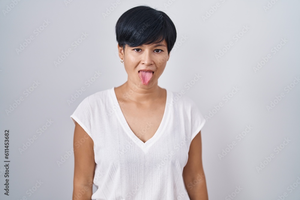 Young asian woman with short hair standing over isolated background sticking tongue out happy with funny expression. emotion concept. Young asian woman with short hair standing over isolated background sticking tongue out happy with funny expression. emotion concept.