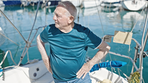 Senior grey-haired man standing with relaxed expression at boat