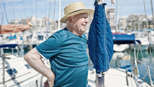 Senior grey-haired man tourist wearing summer hat smiling at boat