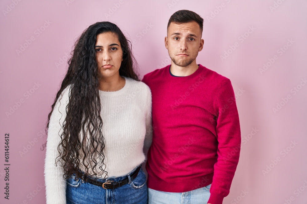 Obraz premium Young hispanic couple standing over pink background depressed and worry for distress, crying angry and afraid. sad expression.