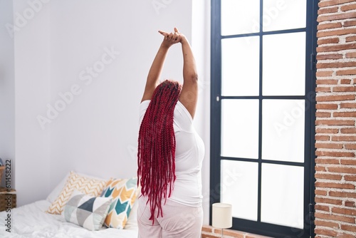 African american woman waking up stretching arms at bedroom photo