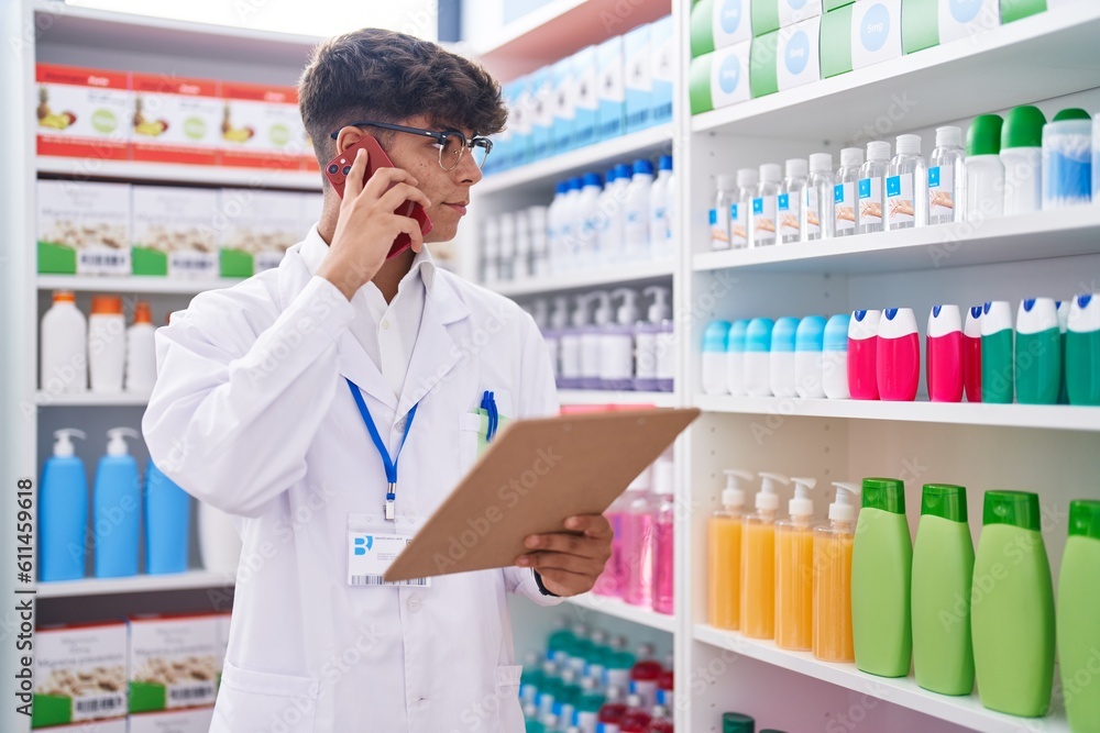 Young hispanic teenager pharmacist talking on smartphone reading document at pharmacy Young hispanic teenager pharmacist talking on smartphone reading document at pharmacy