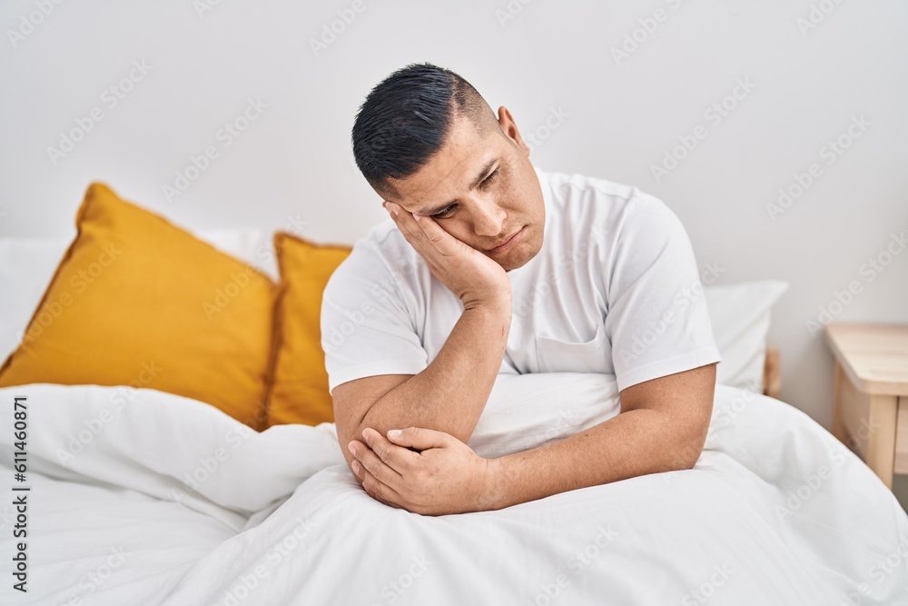 Young latin man stressed sitting on bed at bedroom Young latin man stressed sitting on bed at bedroom