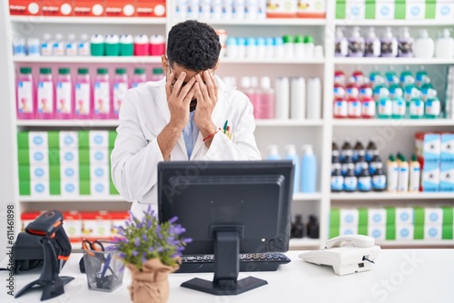 Hispanic man with beard working at pharmacy drugstore with sad expression covering face with hands while crying. depression concept.