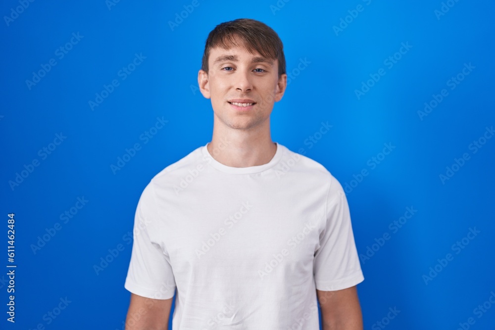 Caucasian blond man standing over blue background with a happy and cool smile on face. lucky person. Caucasian blond man standing over blue background with a happy and cool smile on face. lucky person.