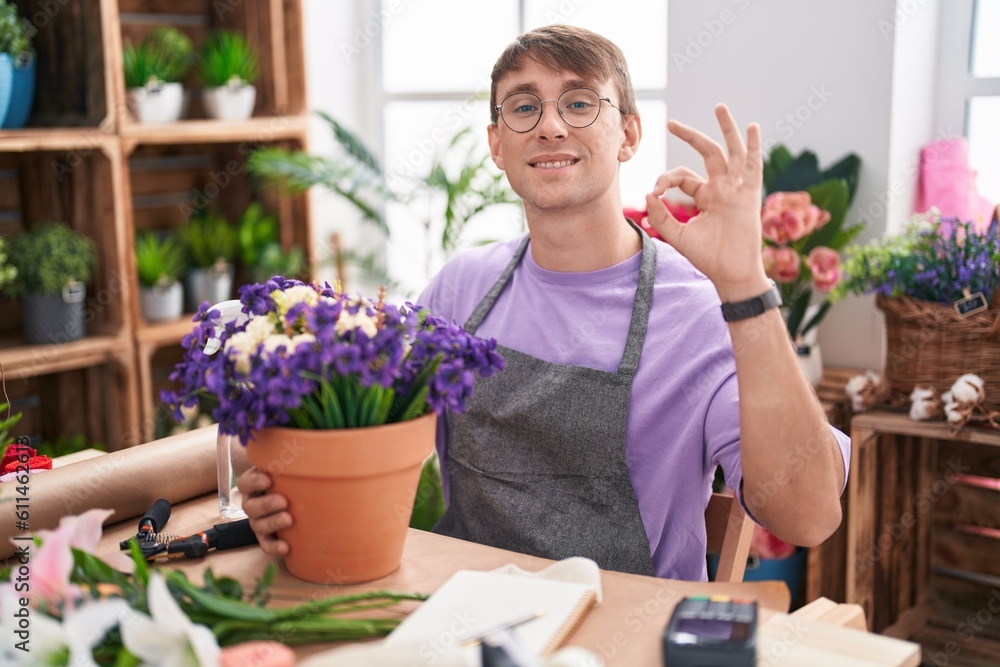 Caucasian blond man working at florist shop smiling positive doing ok sign with hand and fingers. successful expression.