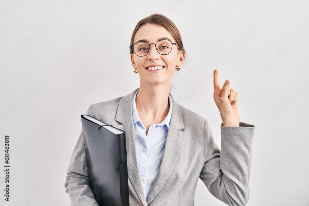 Young caucasian woman wearing business clothes and glasses smiling amazed and surprised and pointing up with fingers and raised arms. Young caucasian woman wearing business clothes and glasses smiling amazed and surprised and pointing up with fingers and raised arms.