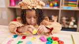 African american girl playing with maths puzzle game sitting on table at kindergarten